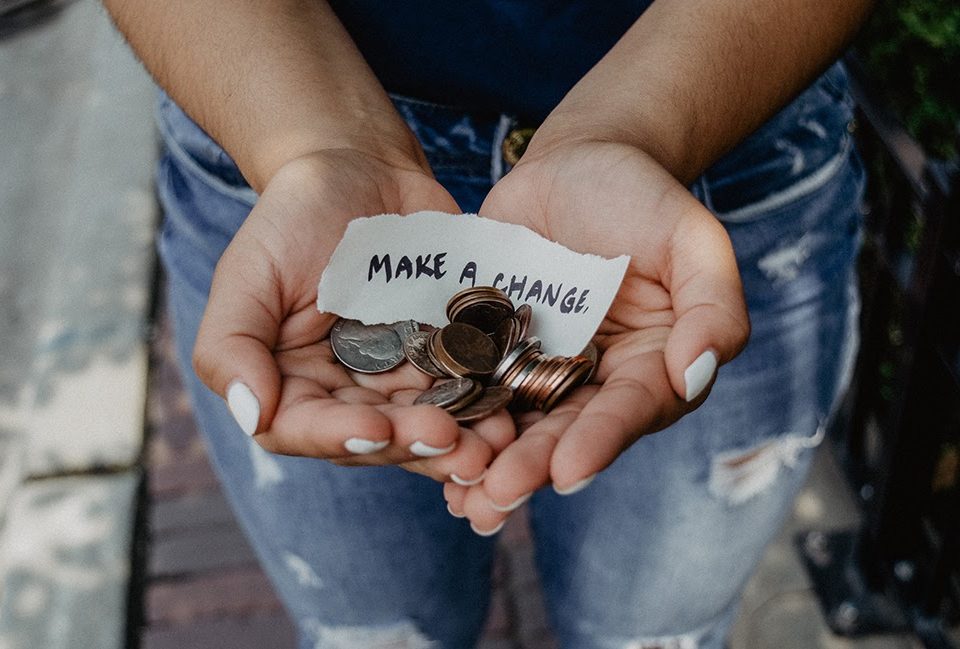 A hand holding some loose change, and a sign reading make a change