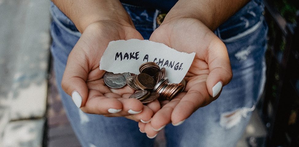 A hand holding some loose change, and a sign reading make a change
